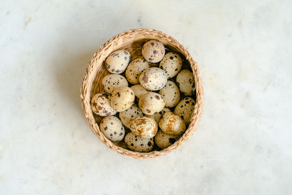 Basket of quail eggs on a marble surface, viewed from above. Perfect for culinary themes.