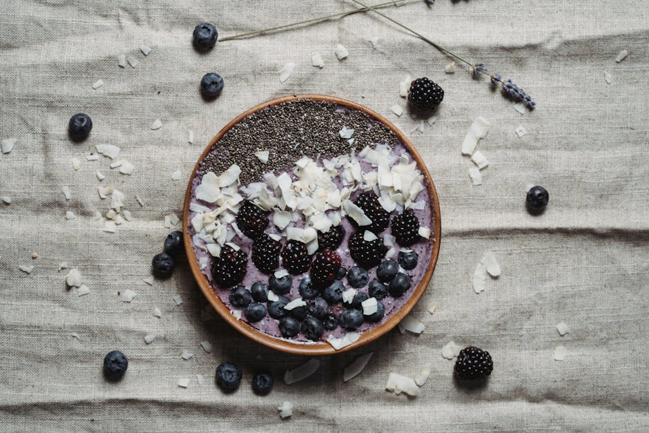 A nutritious berry smoothie bowl topped with chia seeds, blackberries, blueberries, and coconut flakes.
