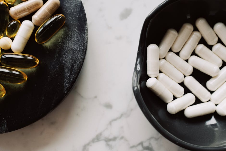 Assorted capsules and pills on black plates, featuring vitamins and supplements.