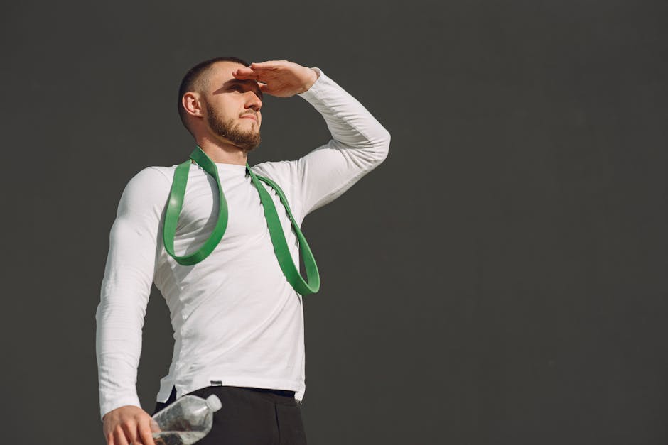 Portrait of a man in sportswear holding a water bottle and resistance band, looking into the distance.