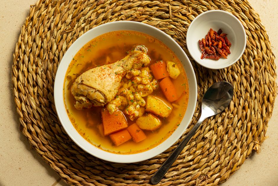 Bowl of vegetable soup with carrots on a woven mat