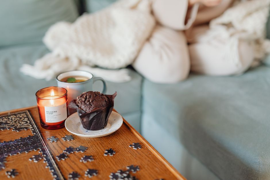 Candle and a warm drink on a cosy blanket-covered table
