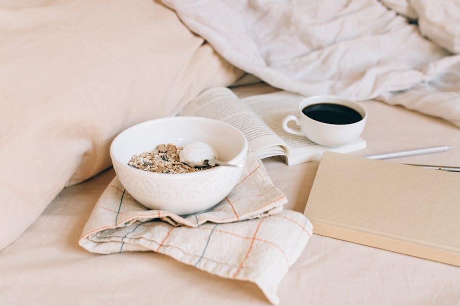 A cozy morning scene featuring a bowl of granola, coffee, and an open book on soft fabrics.