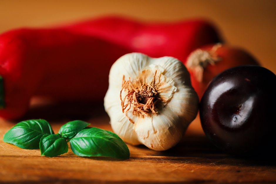 Close-up of fresh basil, garlic, plum, and red pepper for culinary inspiration.