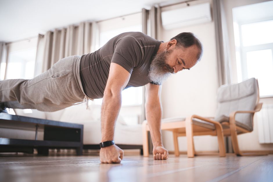 Man doing push-ups on a mat at home in a bright room