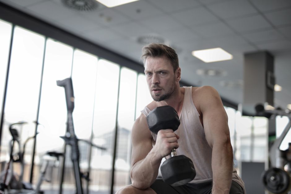 Man lifting a dumbbell in a bright gym