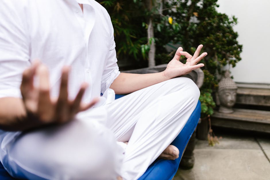A person in white practicing yoga meditation outdoors in a serene environment.