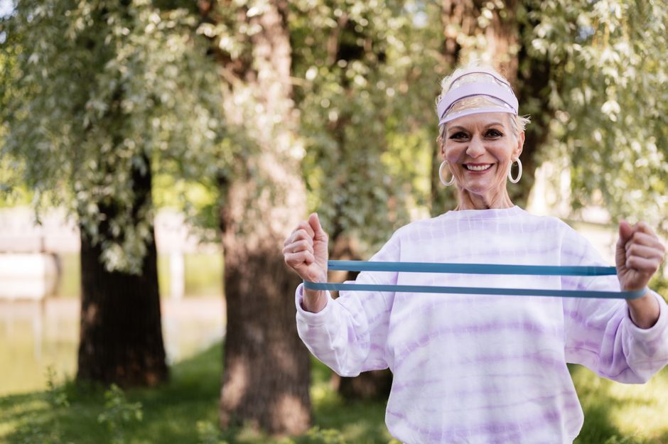 Older woman stretching a resistance band outdoors