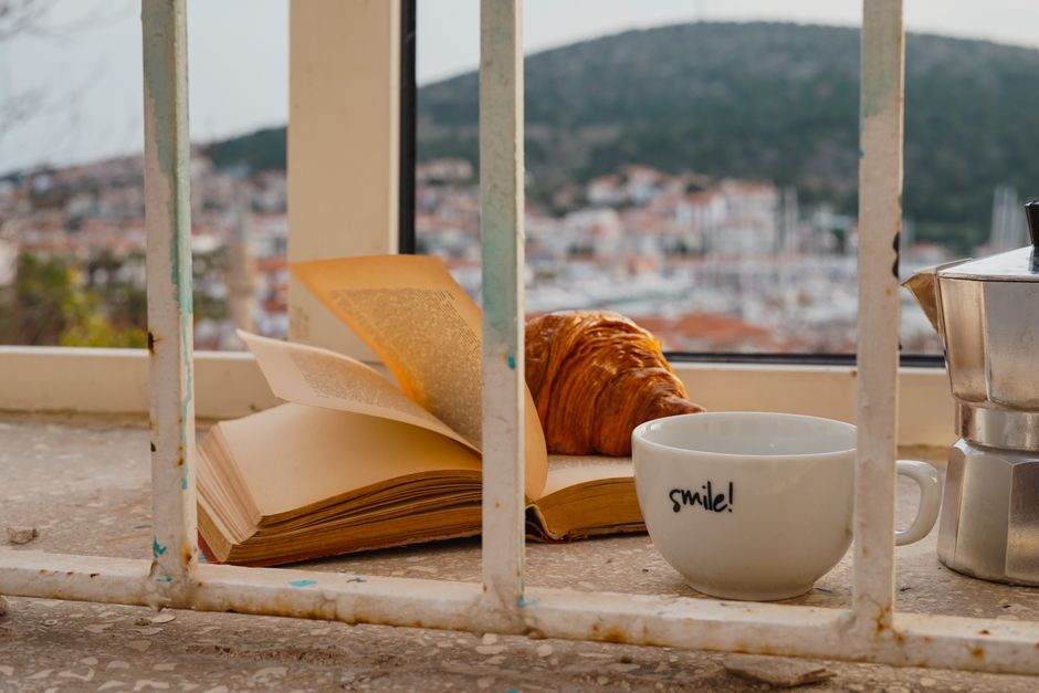 Open book and a cup on a window seat