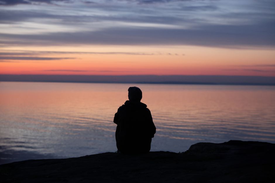 Person sitting calmly by the sea at sunset