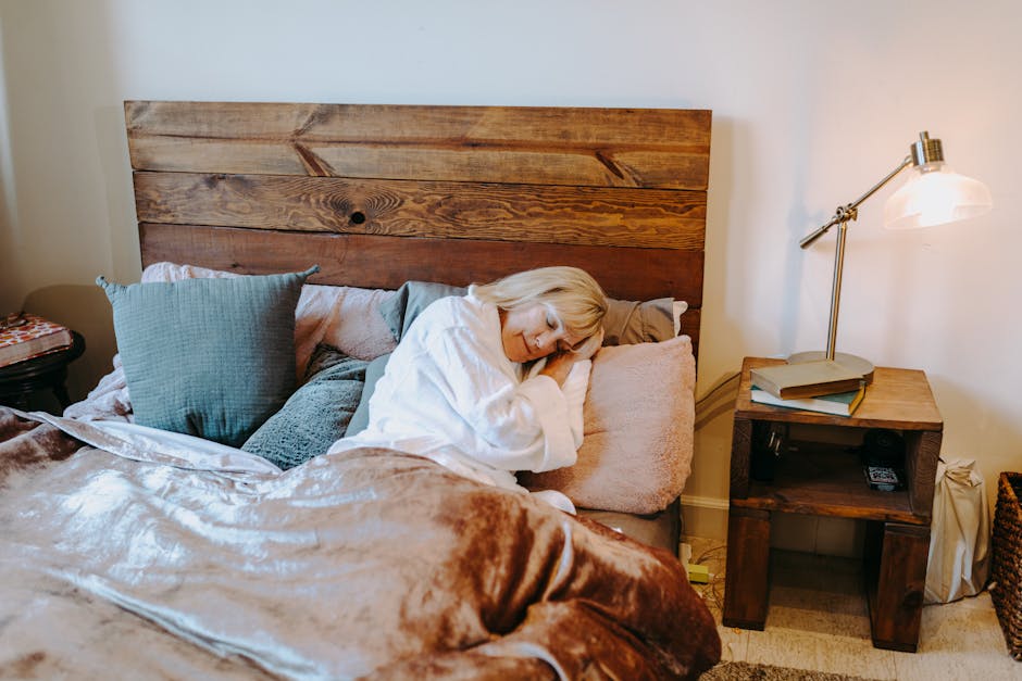 Senior woman resting comfortably in a cozy bedroom setting with soft pillows and warm lighting.