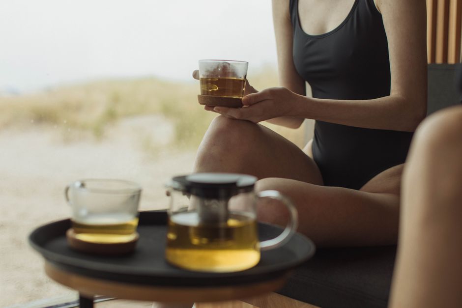 Tea set on a tray beside a person relaxing at home