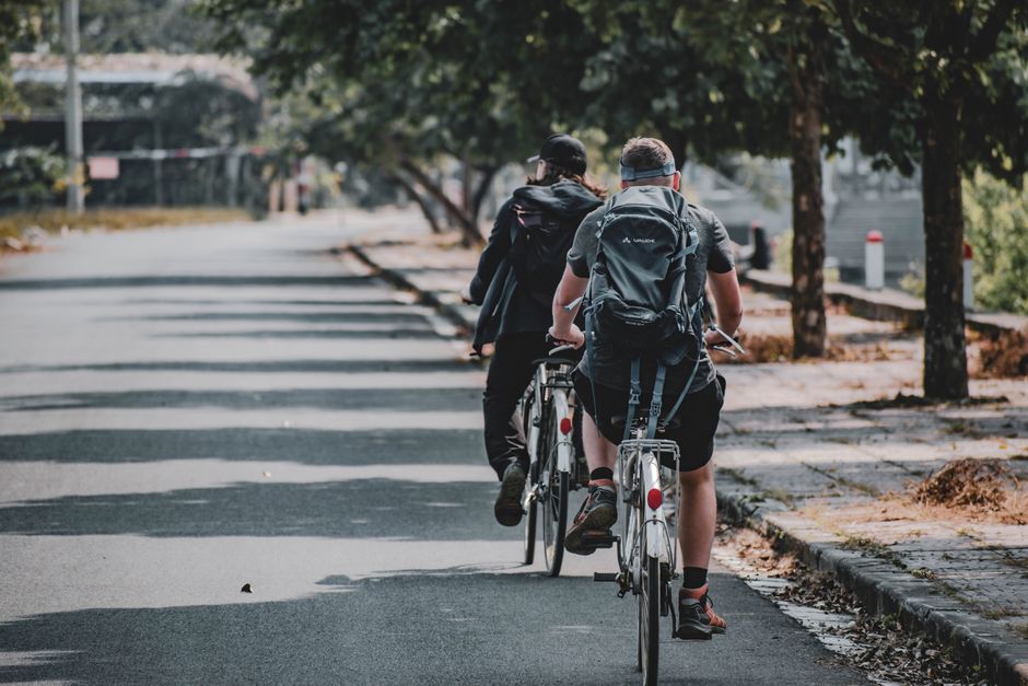 Two cyclists riding along a tree-lined path