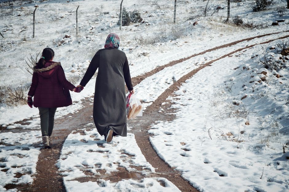 Two people walking along a snowy path outdoors
