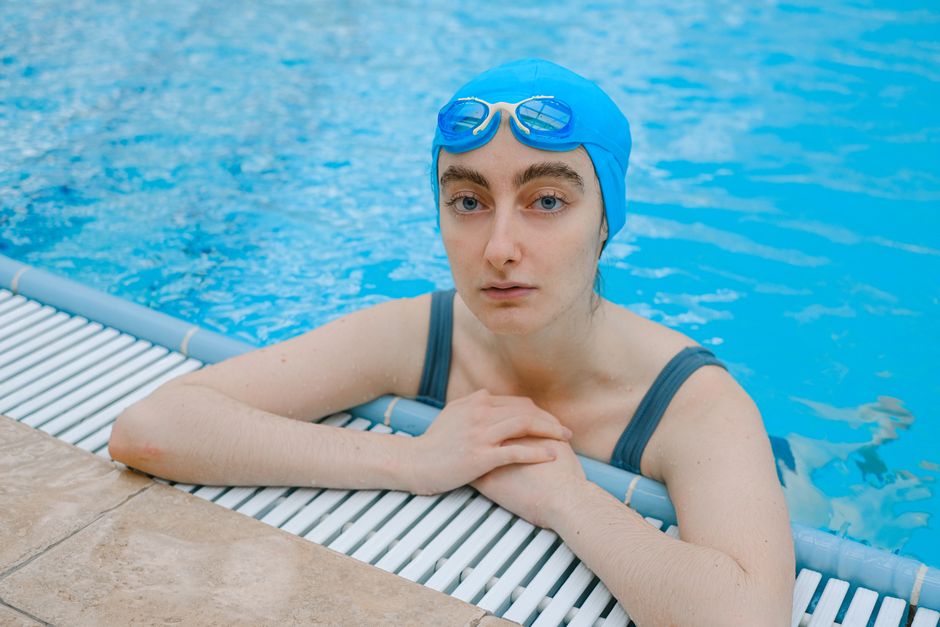 Woman in a swim cap resting at the edge of a pool